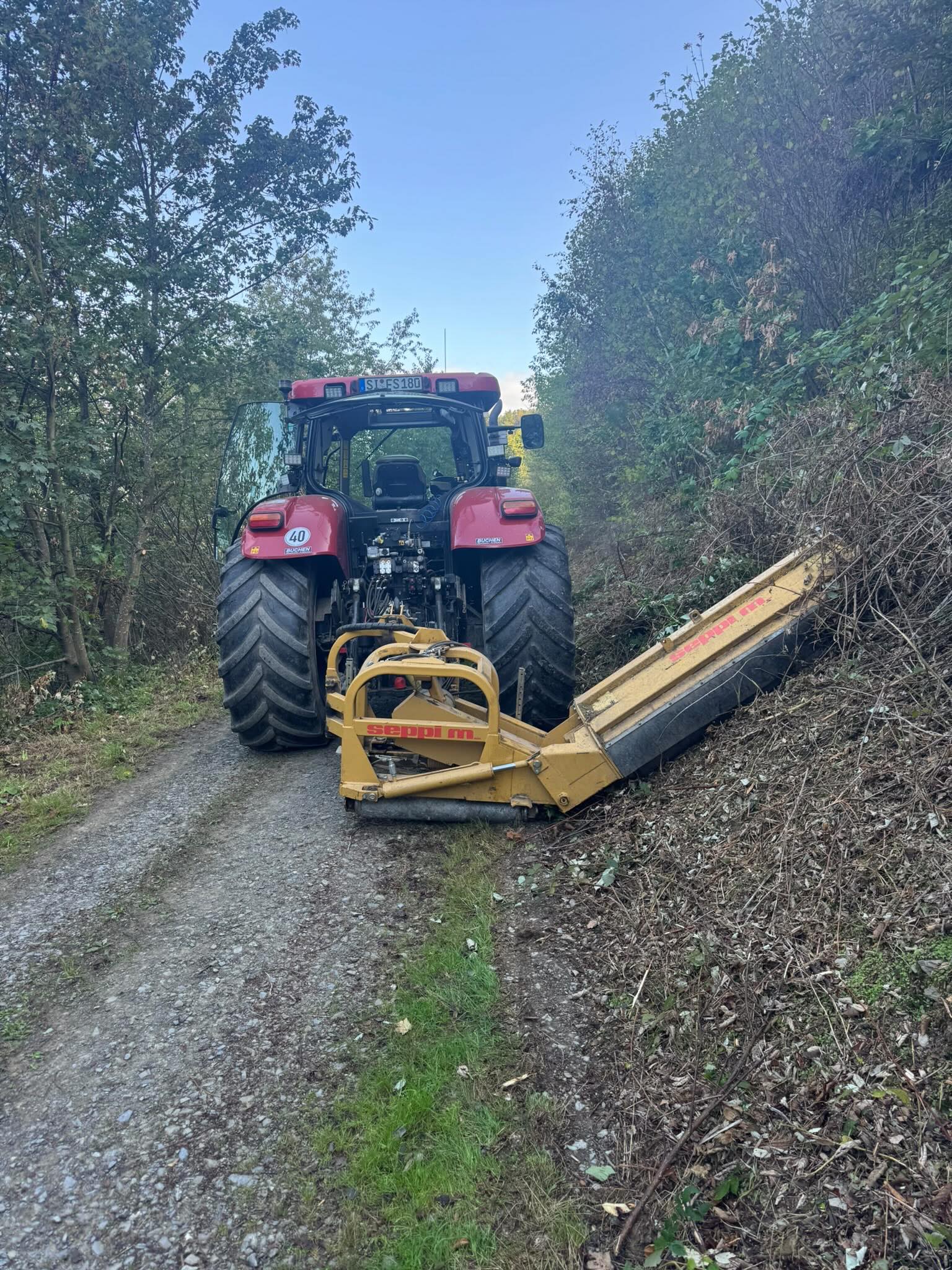 Schlepper mit Auslegemulcher bei der Wegrandpflege am Forstweg